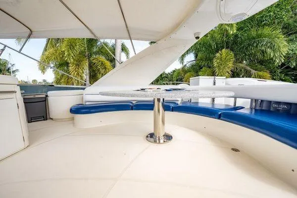The Cure Yacht Photos Pics Luxurious 2003 Azimut 80 Carat yacht deck with blue seating and tropical backdrop.