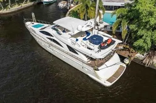 The Cure Yacht Photos Pics 2003 Azimut 80 Carat yacht docked near lush greenery and waterfront property.