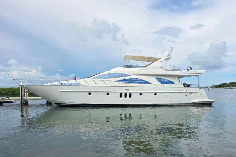 The Cure Yacht Photos Pics Luxury 2003 Azimut 80 Carat yacht on calm water under a cloudy sky.