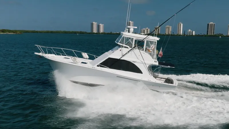 Denise Catherine Yacht Photos Pics 1991 Jersey 42 Convertible Sportfisherman cruising on water with city skyline in background.
