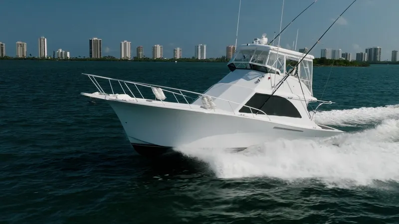Denise Catherine Yacht Photos Pics 1991 Jersey 42 Convertible Sportfisherman cruising on water with city skyline in background.
