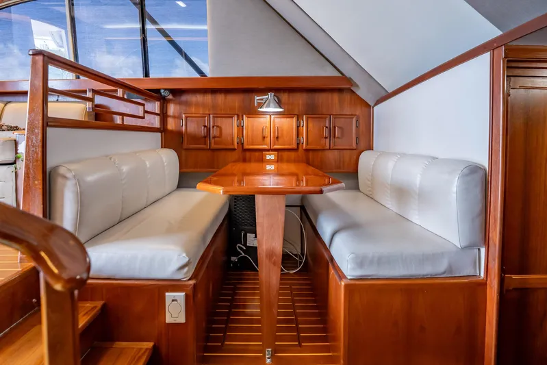 Denise Catherine Yacht Photos Pics Interior of 1991 Jersey 42 Convertible Sportfisherman with wooden dining area and cushioned seating.