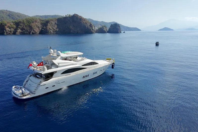 Swordfish 68 Yacht Photos Pics Luxurious 2009 Sunseeker 90 Yacht cruising in serene blue waters near rocky coastline.