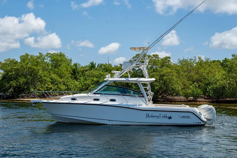  Yacht Photos Pics 2015 Boston Whaler 345 Conquest boat cruising on a sunny day near lush greenery.
