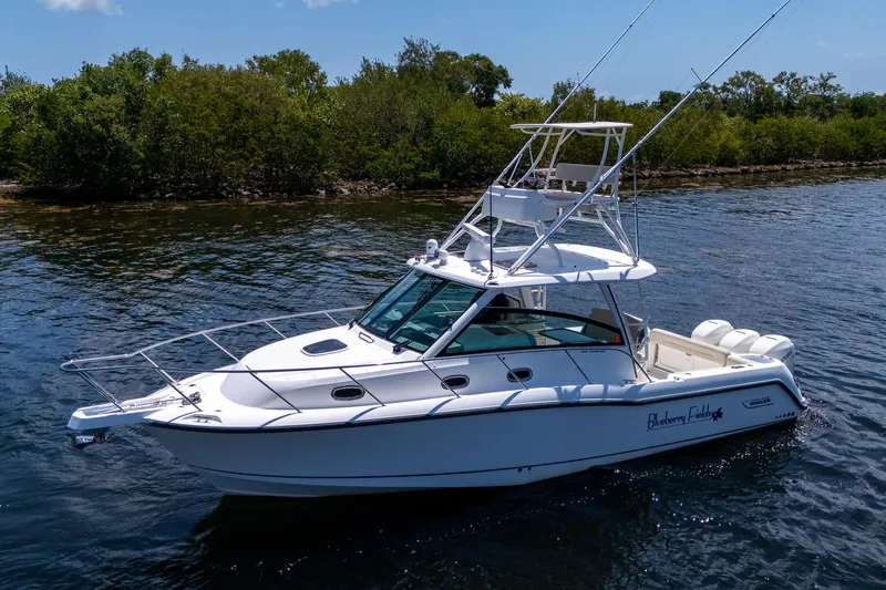  Yacht Photos Pics 2015 Boston Whaler 345 Conquest boat on calm water near lush greenery.
