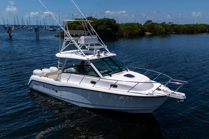  Yacht Photos Pics 2015 Boston Whaler 345 Conquest boat on calm water, surrounded by lush greenery.
