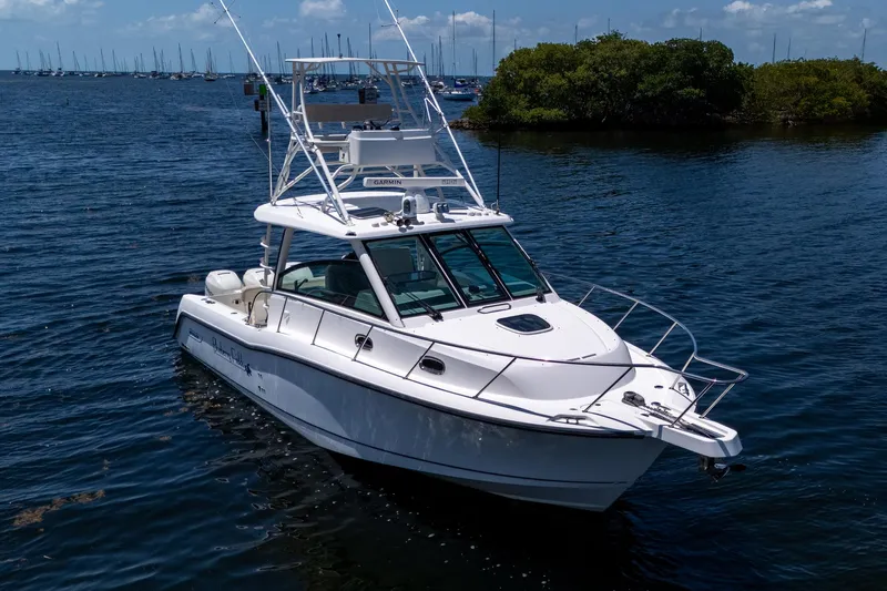  Yacht Photos Pics 2015 Boston Whaler 345 Conquest boat on calm water, surrounded by lush greenery.