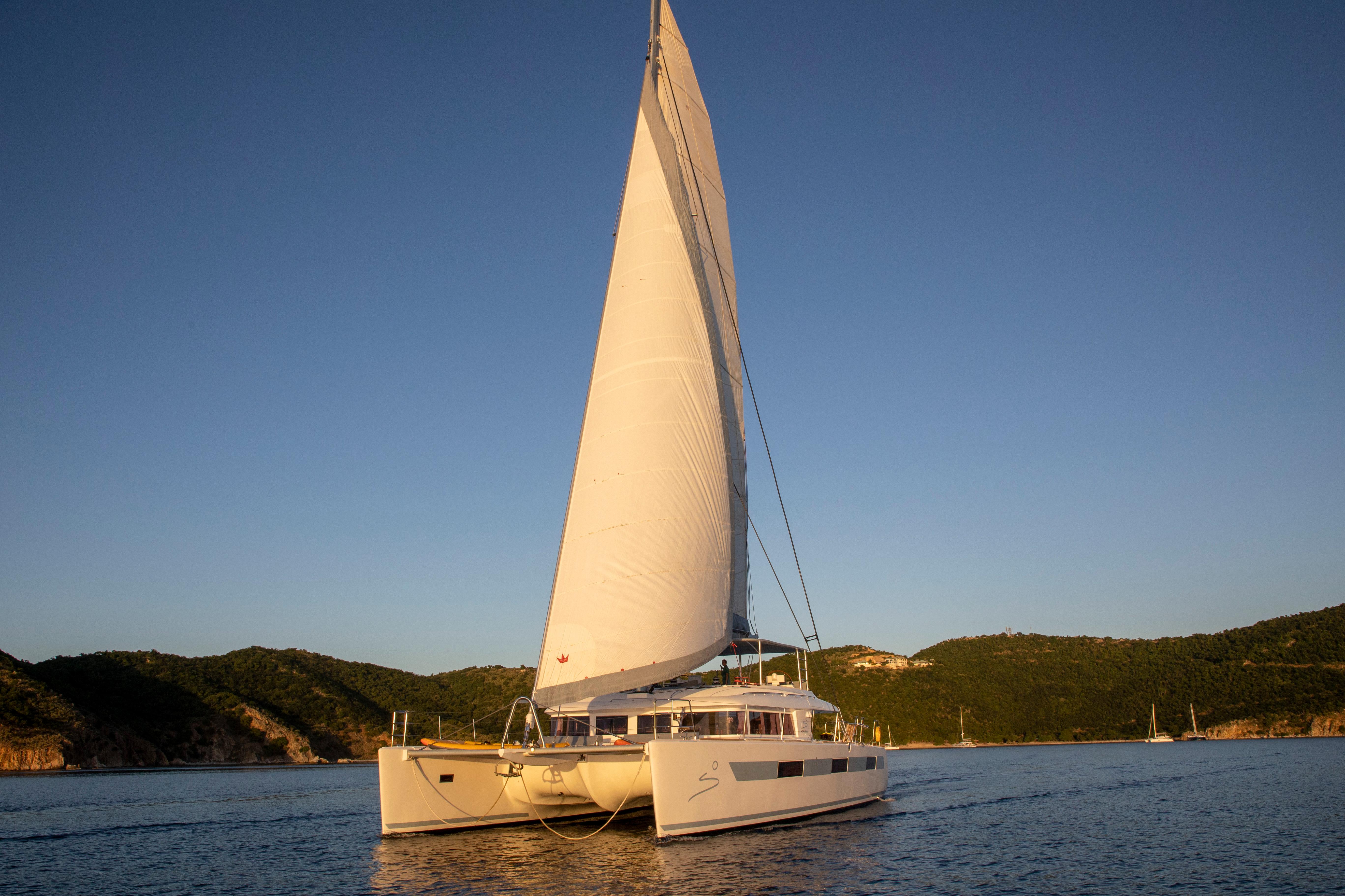 2014 Lagoon 620 catamaran sailing on calm waters at sunset.