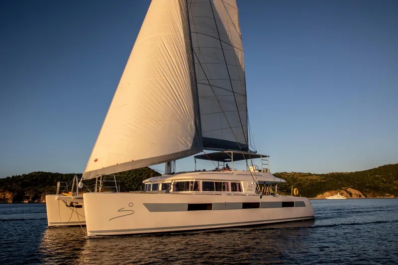 Nomada Yacht Photos Pics Lagoon 620 catamaran sailing on calm waters at sunset, 2014 model.