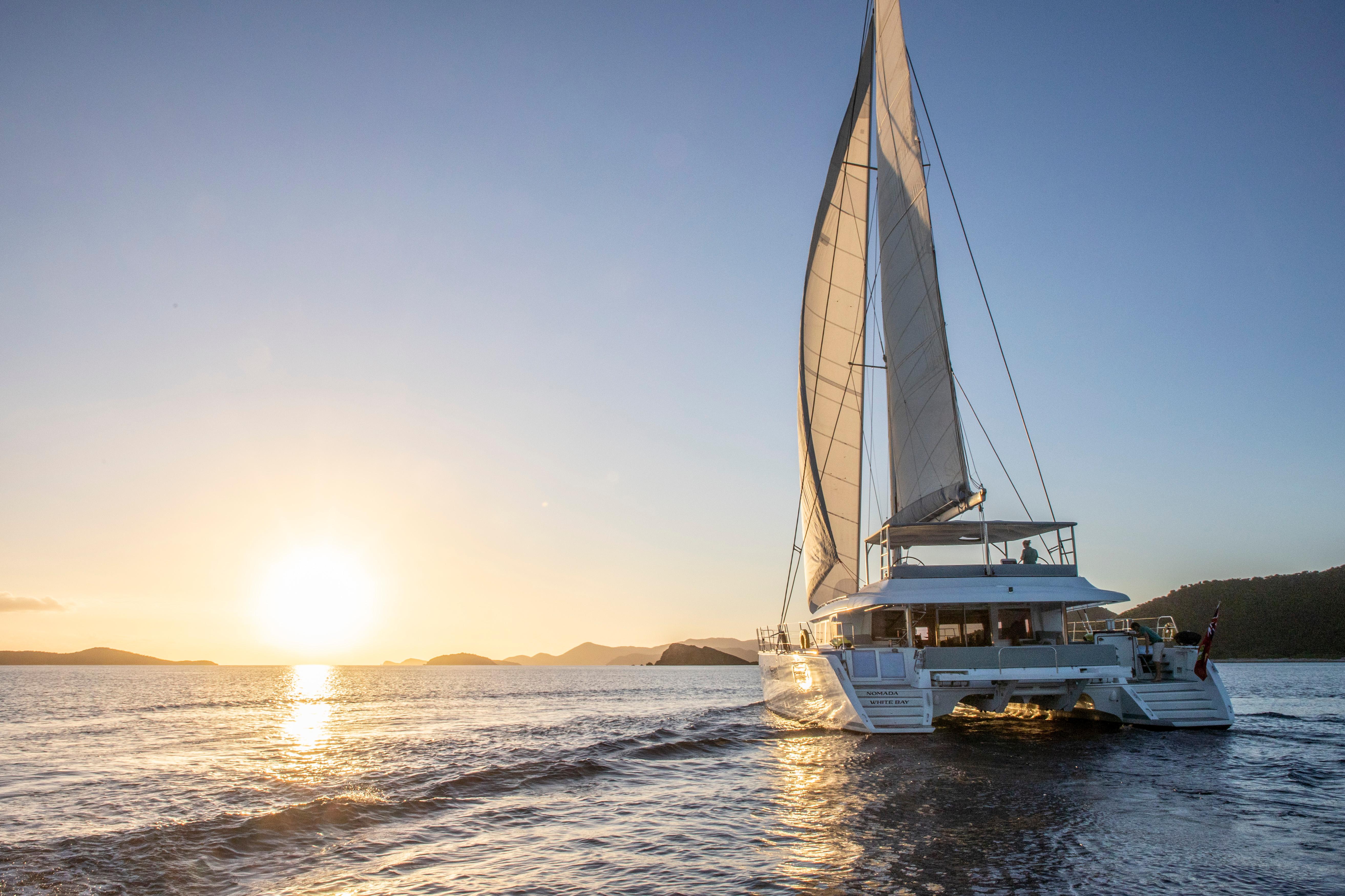 Lagoon 620 catamaran sailing at sunset, 2014 model, on tranquil ocean waters.