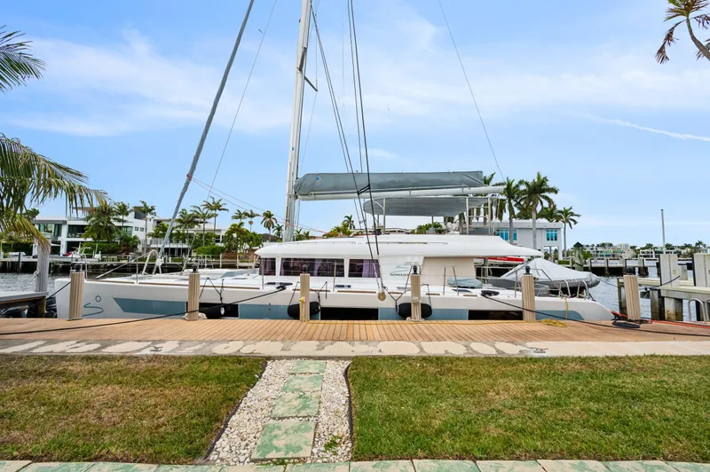 Nomada Yacht Photos Pics Lagoon 620 catamaran docked at marina, 2014 model, surrounded by palm trees and clear skies.