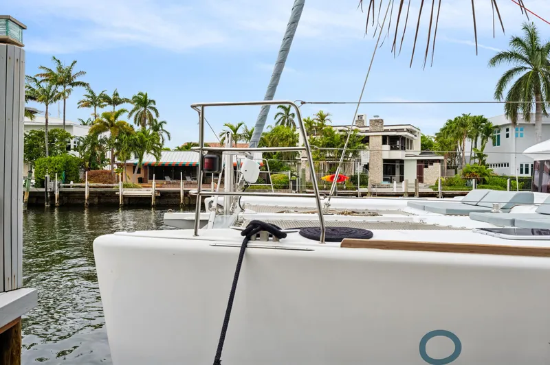 Nomada Yacht Photos Pics Lagoon 620 yacht docked by waterfront homes, surrounded by palm trees, 2014 model.