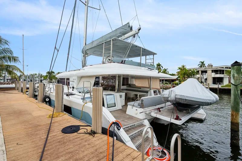 Nomada Yacht Photos Pics Lagoon 620 catamaran docked at marina, 2014 model, with covered tender and spacious deck.
