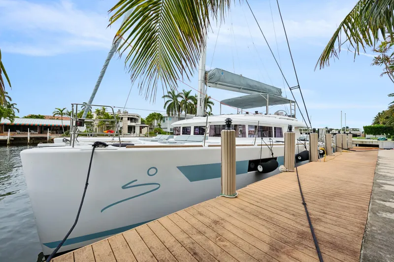 Nomada Yacht Photos Pics Lagoon 620 catamaran docked by palm trees, 2014 model, sunny day.