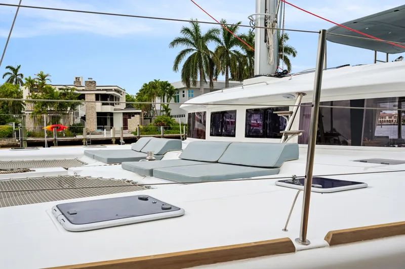 Nomada Yacht Photos Pics Lagoon 620 catamaran 2014, featuring spacious deck with sun loungers, docked near palm trees.