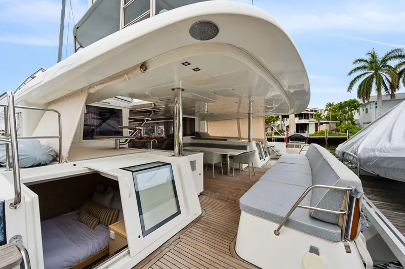 Nomada Yacht Photos Pics Luxurious 2014 Lagoon 620 yacht with spacious deck, seating, and cabin, docked near palm trees.