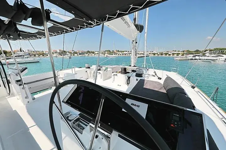 Masterdream Yacht Photos Pics Luxurious 2018 Lagoon 620 Esense yacht cockpit with steering wheel, overlooking marina.