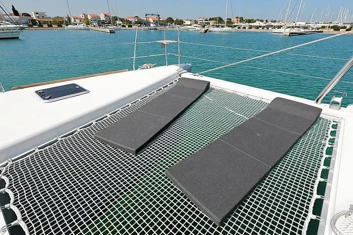 Masterdream Yacht Photos Pics Catamaran Lagoon 620 Esense 2018 with netted deck and cushions, docked in a marina.