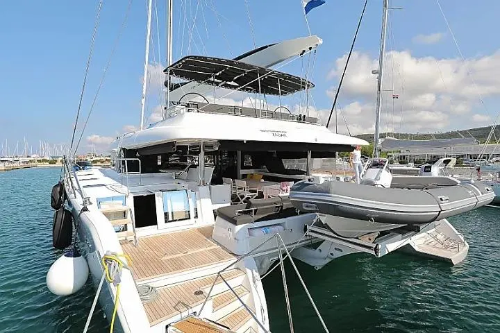 Masterdream Yacht Photos Pics 2018 Lagoon 620 Esense catamaran docked in a marina, featuring spacious deck and tender boat.