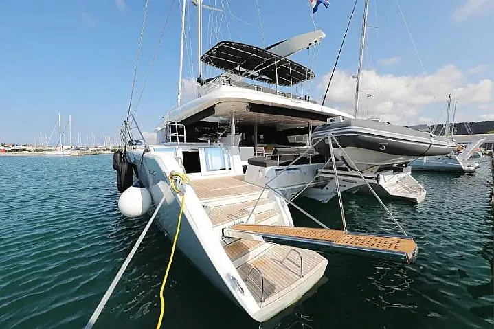 Masterdream Yacht Photos Pics 2018 Lagoon 620 Esense catamaran docked in a marina, featuring a spacious deck and tender.