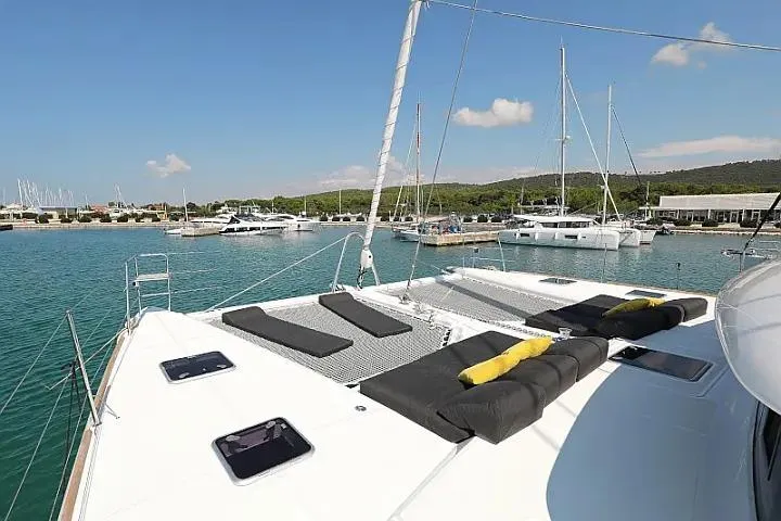 Masterdream Yacht Photos Pics 2018 Lagoon 620 Esense catamaran with sunbathing area, docked in a serene marina.