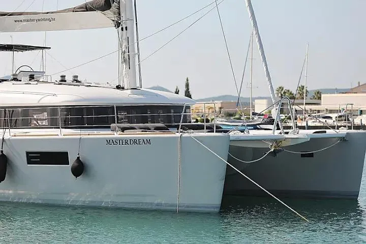 Masterdream Yacht Photos Pics 2018 Lagoon 620 Esense catamaran docked in a marina, side view.