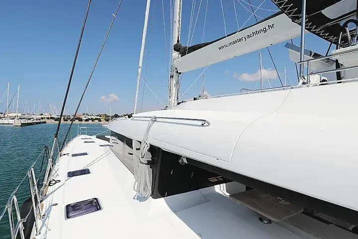 Masterdream Yacht Photos Pics 2018 Lagoon 620 Esense yacht deck with sails, docked in a marina.