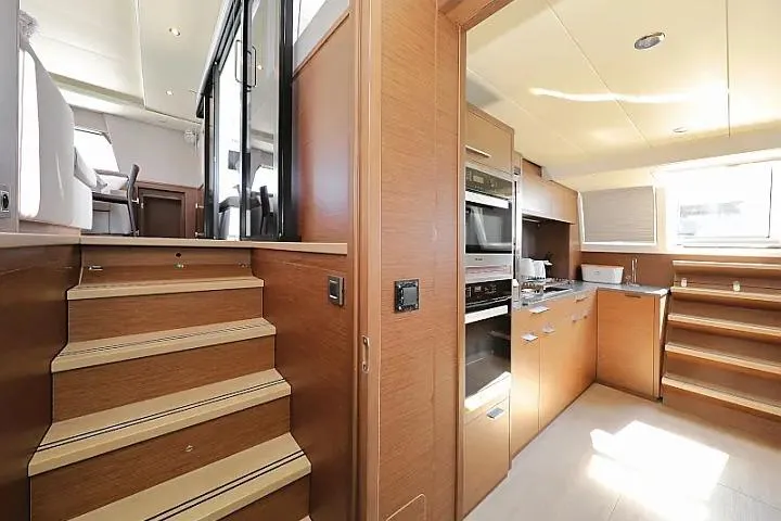 Masterdream Yacht Photos Pics Luxurious interior of 2018 Lagoon 620 Esense yacht with modern kitchen and wooden stairs.