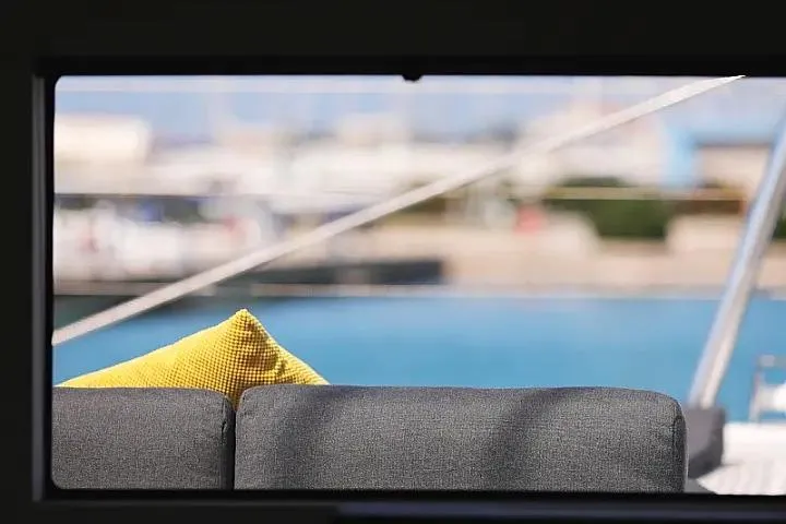 Masterdream Yacht Photos Pics Lagoon 620 Esense 2018 yacht interior with gray sofa and yellow cushion, marina view.