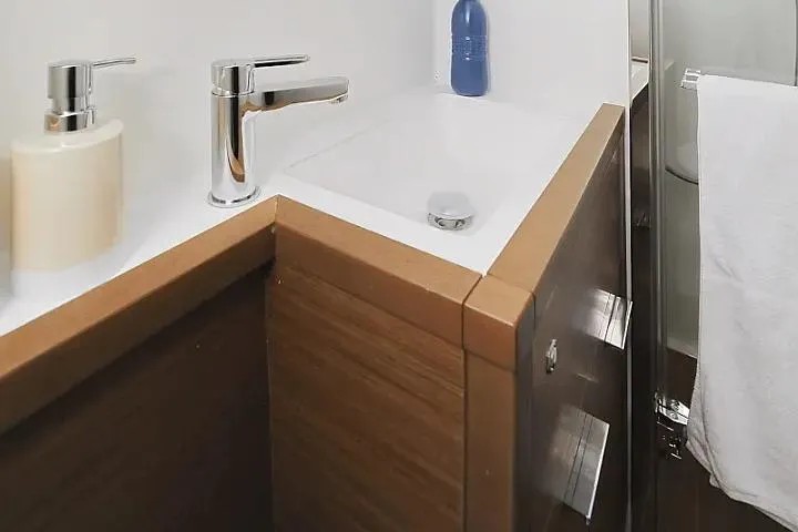 Masterdream Yacht Photos Pics Modern bathroom sink on 2018 Lagoon 620 Esense yacht, featuring sleek faucet and wooden cabinetry.
