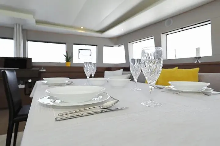 Masterdream Yacht Photos Pics Elegant dining area inside 2018 Lagoon 620 Esense yacht, featuring crystal glassware and modern decor.