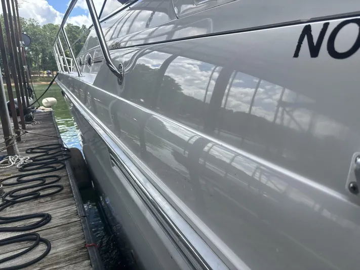 Forget About It Yacht Photos Pics Side view of a 1996 Sea Ray 500 Sundancer docked by a wooden pier.