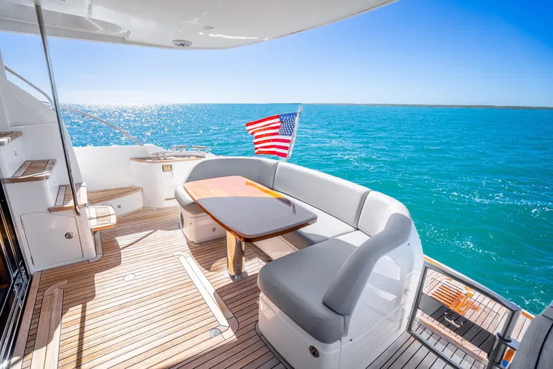 Chill Yacht Photos Pics Luxurious 2018 Princess F49 yacht deck with seating, ocean view, and American flag.