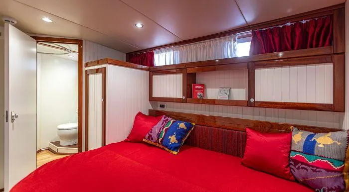 Sally Yacht Photos Pics Cozy 1959 Burger 60 yacht cabin with red bedding, colorful pillows, and ensuite bathroom.