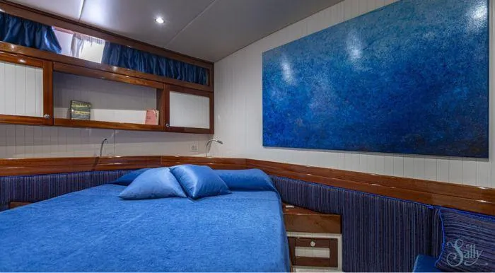Sally Yacht Photos Pics Cozy yacht cabin with blue decor, wooden accents, and abstract wall art. Burger 60, 1959 model.