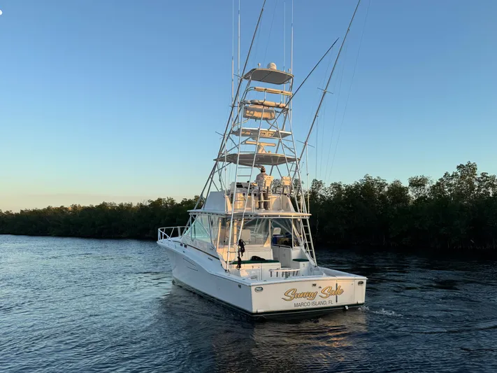  Yacht Photos Pics 1999 Cabo 45 Express yacht cruising on a calm river at sunset.