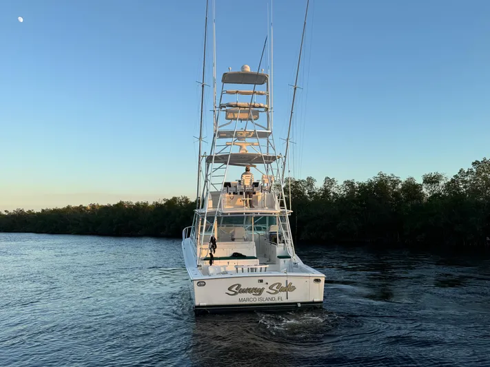  Yacht Photos Pics 1999 Cabo 45 Express boat cruising on a calm river at sunset.