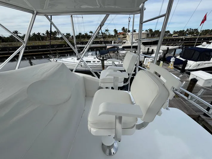  Yacht Photos Pics 1999 Cabo 45 Express yacht with white seating on the deck, docked at a marina.