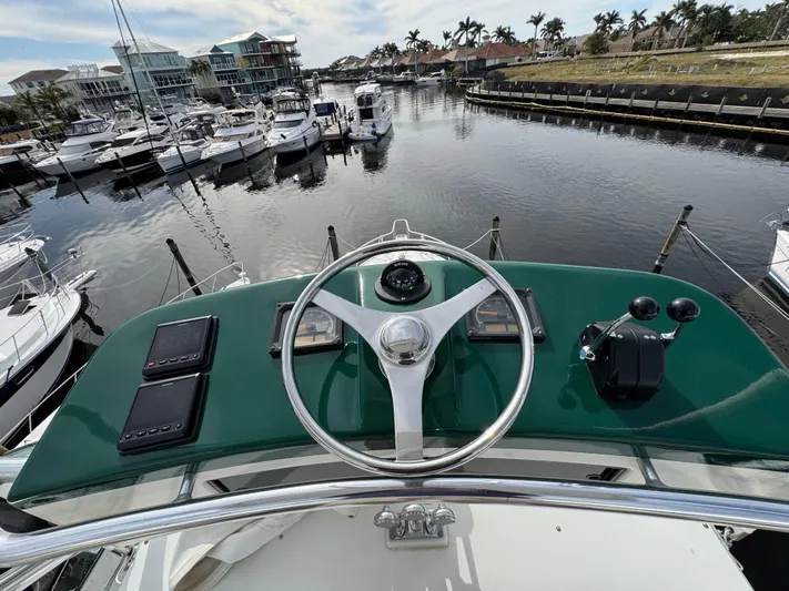  Yacht Photos Pics Helm of 1999 Cabo 45 Express yacht overlooking marina with boats and palm trees.