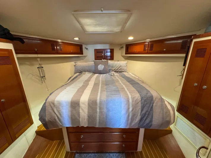  Yacht Photos Pics Cozy cabin interior of 1999 Cabo 45 Express with striped bedding and wooden storage.