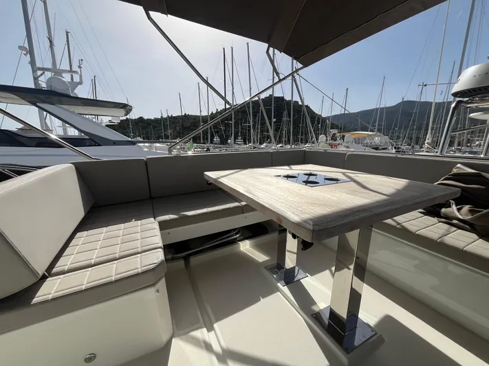  Yacht Photos Pics Luxury seating area on 2018 Prestige 520 yacht, featuring elegant table and marina backdrop.