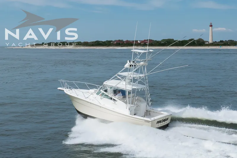 Pipe Dream Yacht Photos Pics 2005 Topaz 32 Express yacht cruising near a lighthouse on open water.