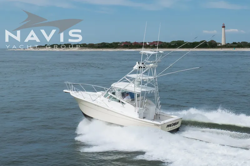 Pipe Dream Yacht Photos Pics 2005 Topaz 32 Express yacht cruising near a lighthouse on a sunny day.