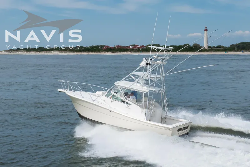 Pipe Dream Yacht Photos Pics 2005 Topaz 32 Express yacht cruising near a lighthouse, Navis Yacht Group logo visible.