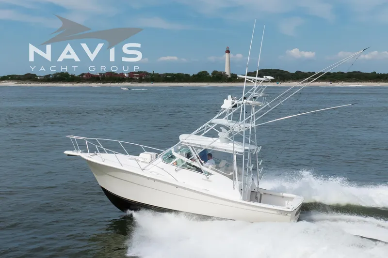 Pipe Dream Yacht Photos Pics 2005 Topaz 32 Express yacht cruising near a lighthouse, Navis Yacht Group logo visible.