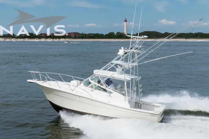 Pipe Dream Yacht Photos Pics 2005 Topaz 32 Express yacht cruising near a lighthouse on a sunny day.