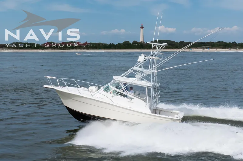 Pipe Dream Yacht Photos Pics 2005 Topaz 32 Express yacht cruising near a lighthouse on a sunny day.