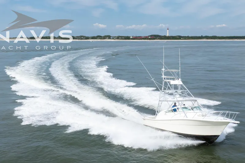 Pipe Dream Yacht Photos Pics 2005 Topaz 32 Express yacht cruising on open water with lighthouse in background.