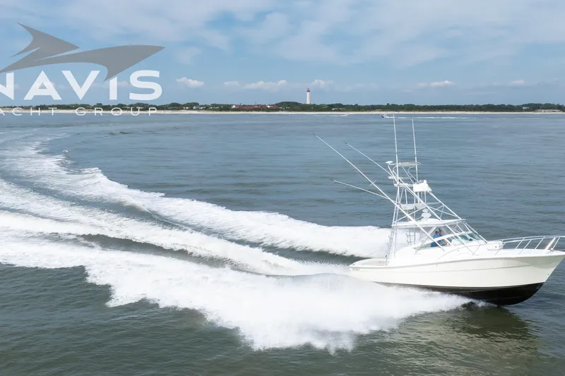 Pipe Dream Yacht Photos Pics 2005 Topaz 32 Express yacht cruising on open water with lighthouse in background.