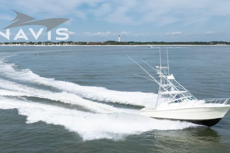 Pipe Dream Yacht Photos Pics 2005 Topaz 32 Express yacht cruising on open water with lighthouse in background.
